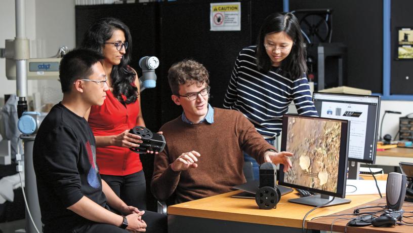 Prof. Carl Vondrick working in his lab with three researchers.