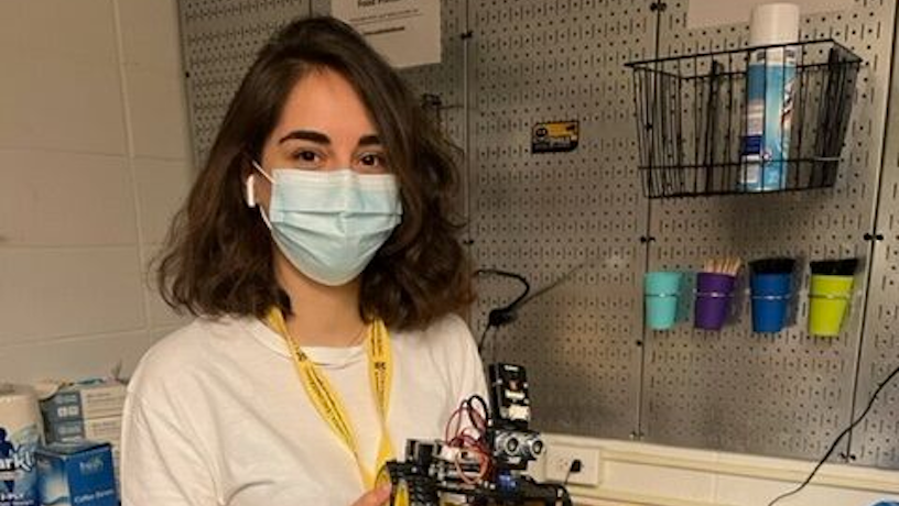 A SHAPE student holding up a robot prototype.