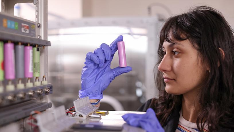 A student holding up an 18650-format lithium-ion battery close to their face