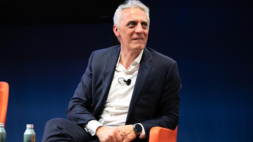 A male panelist sitting in a chair on-stage.
