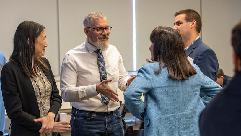 Four people conversing. The central person smiles and gestures.