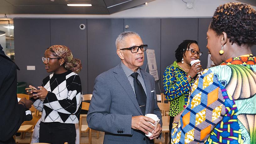 Four people holding disposable coffee cups and exchanging conversation