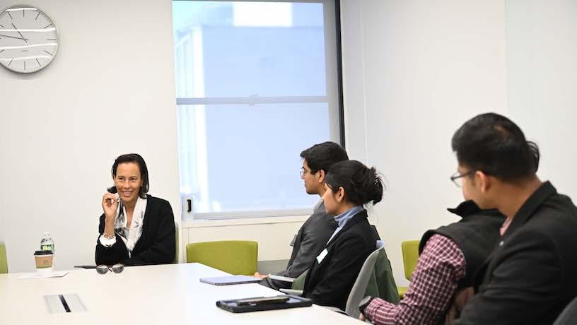 Anne Gates sitting at a table. Four Columbia Engineering students sit to her right and look at her.