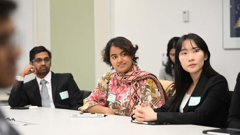 Three students sitting at a table looking in the same direction.