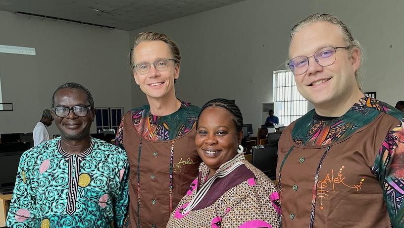 Four people smiling for a photo in a classroom